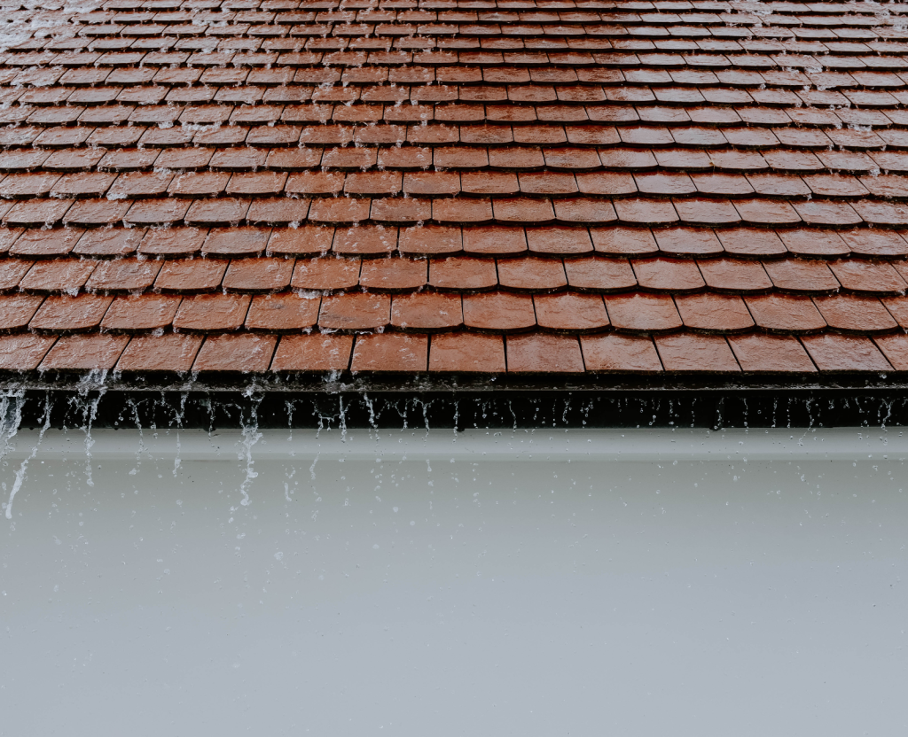 Rainwater flowing down from a pitched roof onto a flat roof
